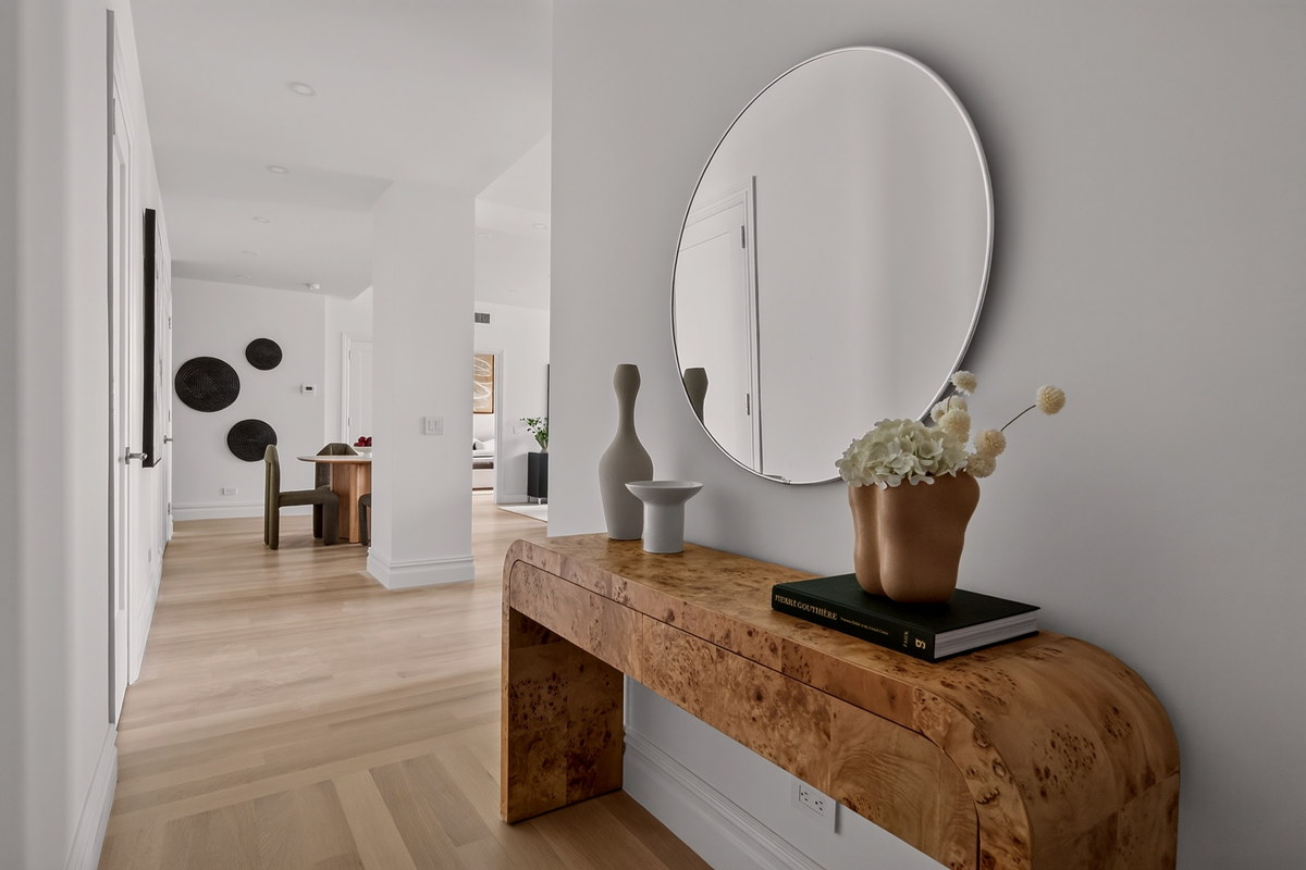 Foyer with burl wood console, round mirror, and view through to dining nook