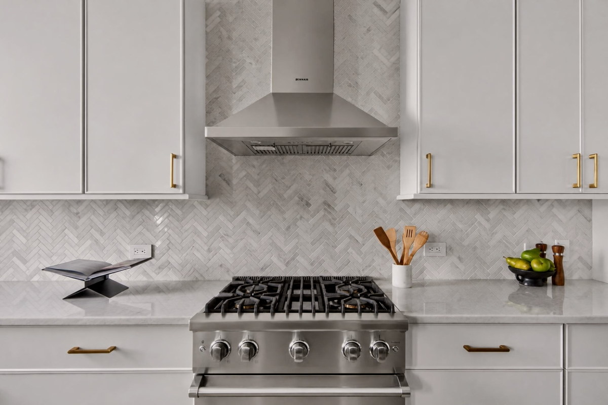Kitchen detail with stainless hood and marble herringbone backsplash